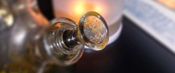 Rusty glass bottle opener on a dark surface, vintage style, close-up image.