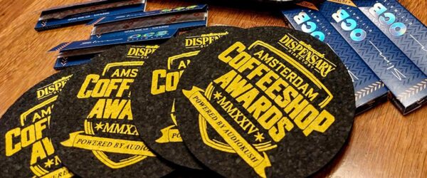 High-quality coffer shop coasters with vibrant yellow print, branded with Amsterdam Coffee Shop, MMXXV, powered by AudioKush, ideal for coffee shops, cafes, and promotional events.