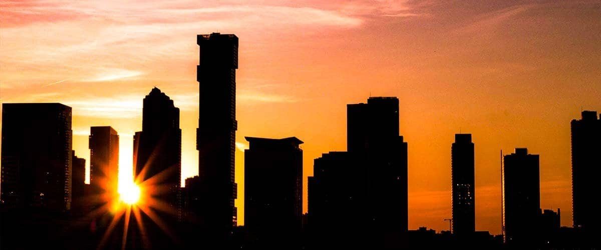 Silhouette of city skyscrapers during sunset, vibrant orange and purple sky, urban sunset scene, city skyline with tall buildings at dusk, modern city architecture background.