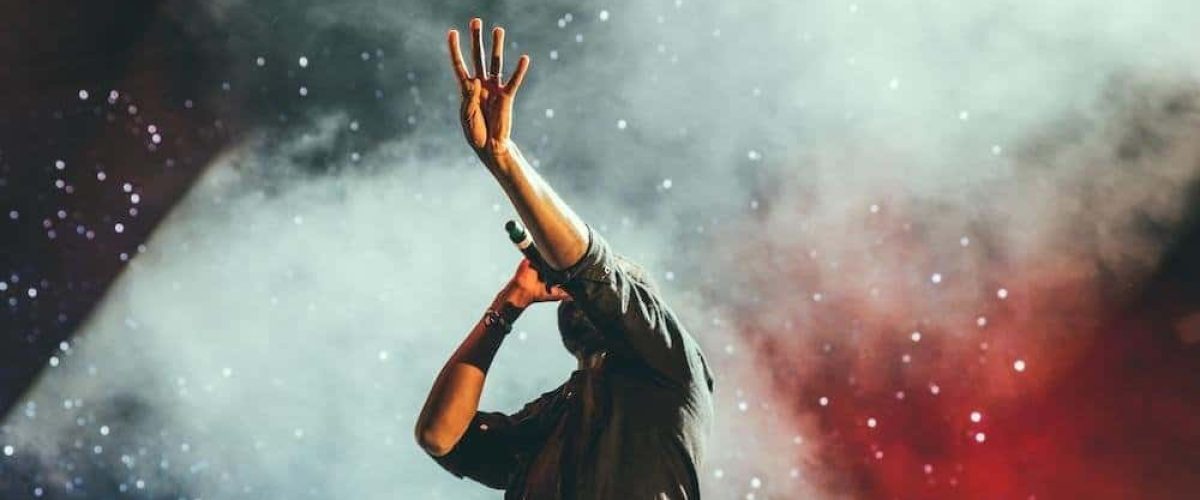 Vibrant live concert performer on stage with colorful lighting and smoke effects, creating an energetic atmosphere for music lovers and audio enthusiasts.