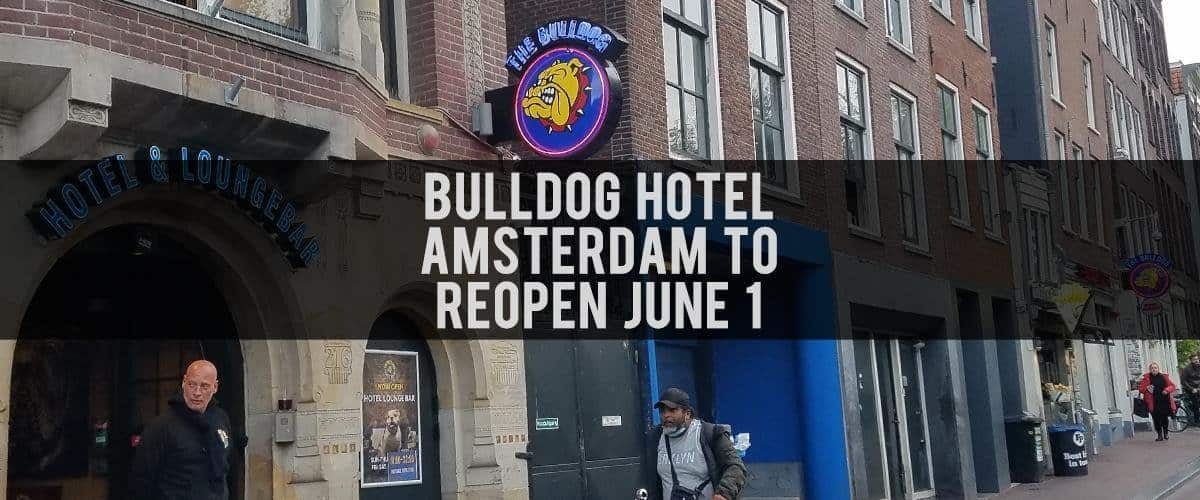 Audiokush logo with Bulldog Hotel Amsterdam reopening announcement, neon sign, city street scene, pedestrians, vibrant urban atmosphere, exhibition, entertainment, entertainment venue exterior.
