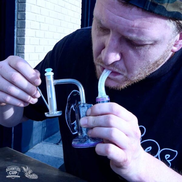 Man vaporizes solventless rosin dabs on a terp slurper banger with a glass rig