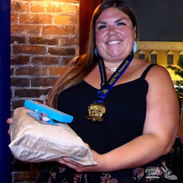 Woman poses with prizes and medal at Solventless Cup cannabis awards ceremony